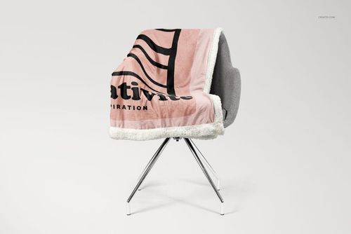 Pink and black patterned sherpa blanket mockup displayed on a contemporary gray chair, side perspective.