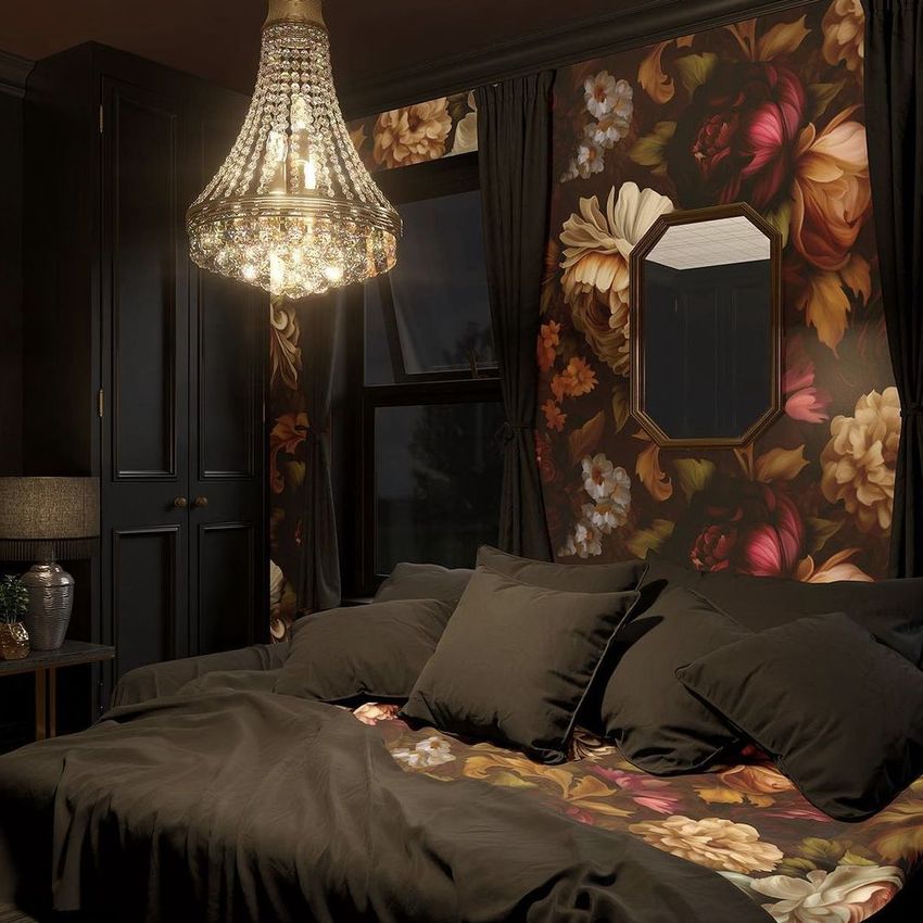 Bedroom mockup featuring a dark floral wallpaper and bedding, with a crystal chandelier above a bed and dark curtains framing a window.