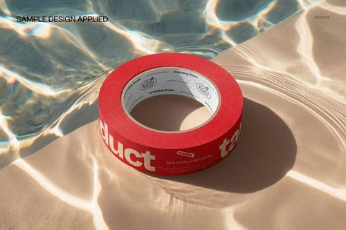 Red packaging tape roll with white inner label resting on a sunlit poolside surface, shown in a PSD mockup scene.