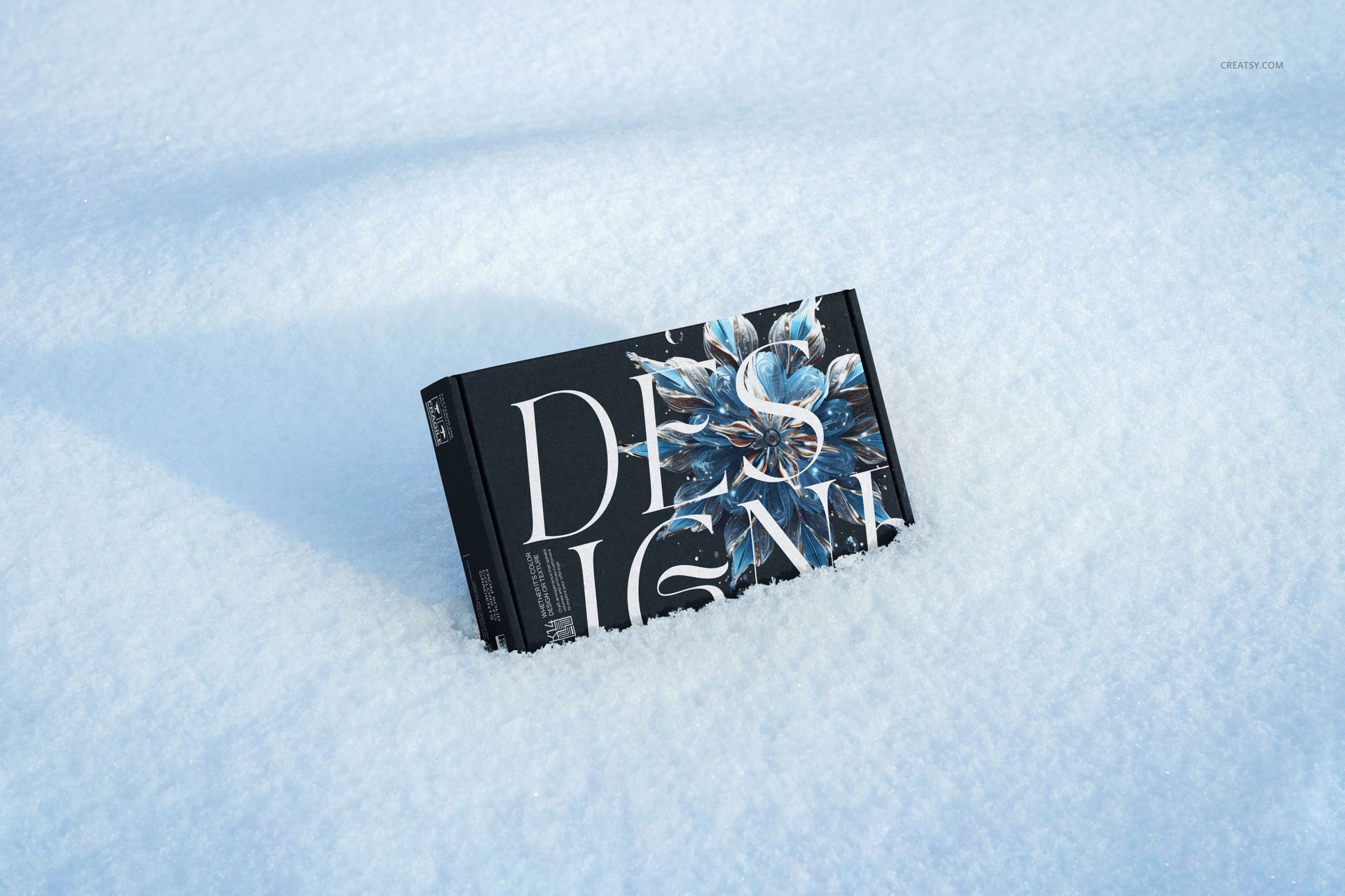 Winter-themed mailing box mockup featuring a dark floral pattern, shown half-buried in clean snow from a side angle.