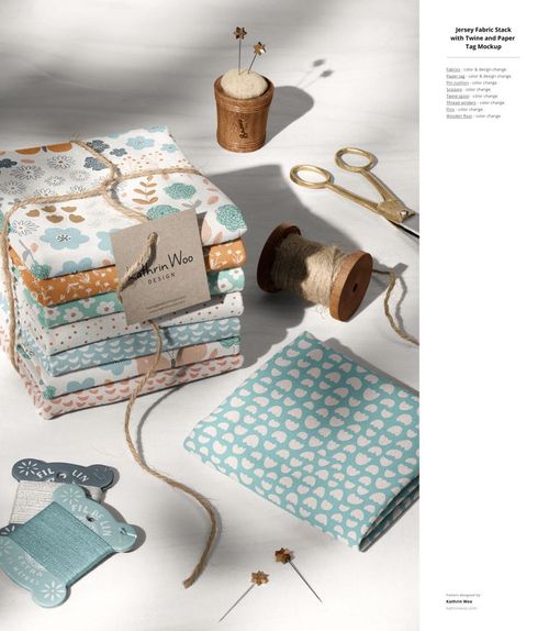 PSD mockup featuring layered jersey fabrics with floral and geometric prints, surrounded by sewing accessories and sunlight.