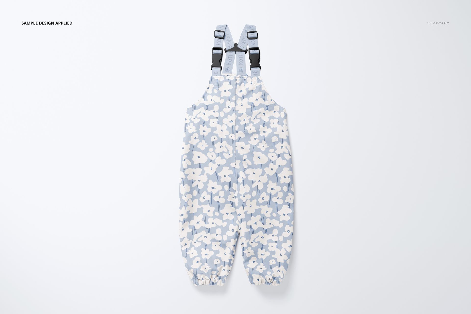 Kids rainwear mockup featuring overalls with adjustable black straps and a soft blue and white flower design.
