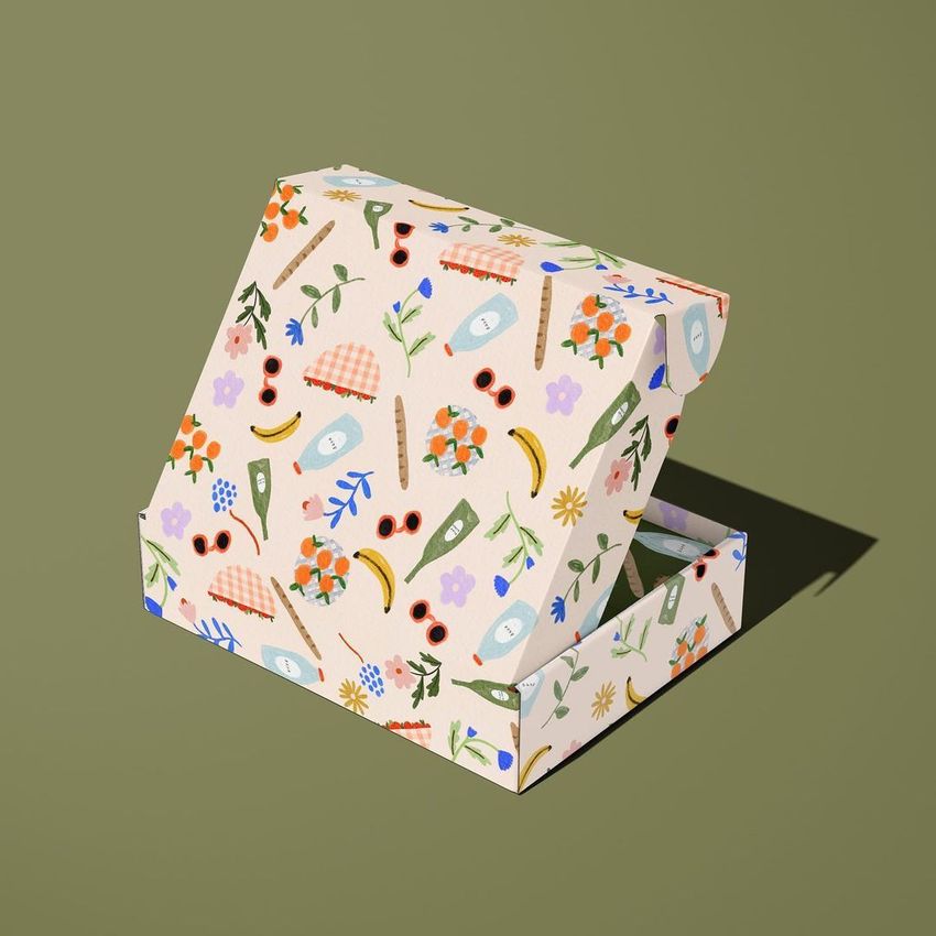 Mailing box mockup featuring a colorful picnic-themed pattern with fruits, flowers, and tableware on a light background.