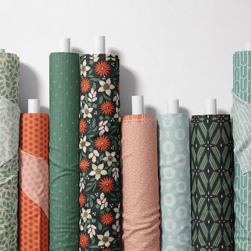 Fabric rolls mockup showing eight upright rolls with various colorful patterns, including florals, geometrics, and abstract designs.