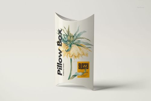 Front view of a standing pillow box mockup with glossy finish, yellow flower artwork, and black lettering on white.