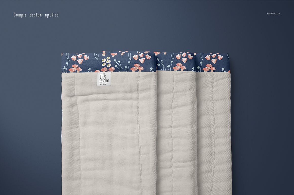 Burp cloth mockup featuring a folded beige cloth with a patterned blue top edge, shown from a top view on a blue background.
