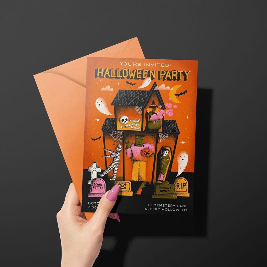 Greeting card mockup featuring a woman's hand holding a Halloween-themed invitation with an orange envelope on a dark background.