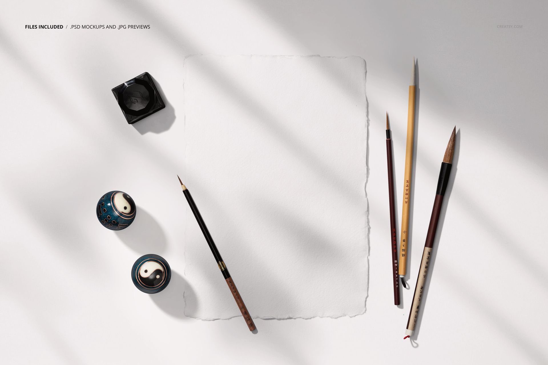 Japanese calligraphy PSD mockup featuring empty paper, assorted brushes, ink container, and ceramic pieces in sunlight.