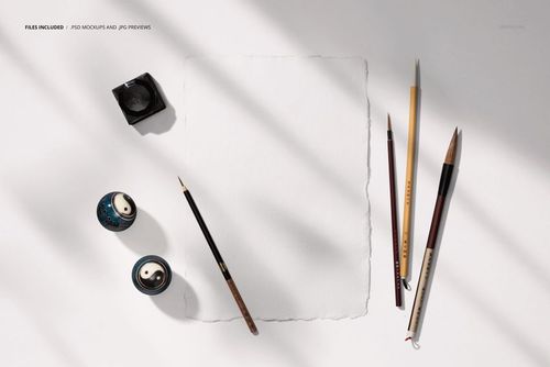 Japanese calligraphy PSD mockup featuring empty paper, assorted brushes, ink container, and ceramic pieces in sunlight.