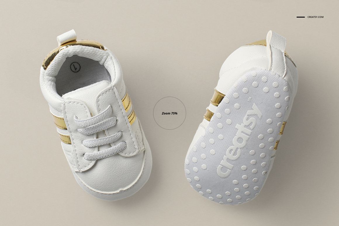Top view of two white baby shoes with gold accents, one showing the sole with dotted texture and the other upright.