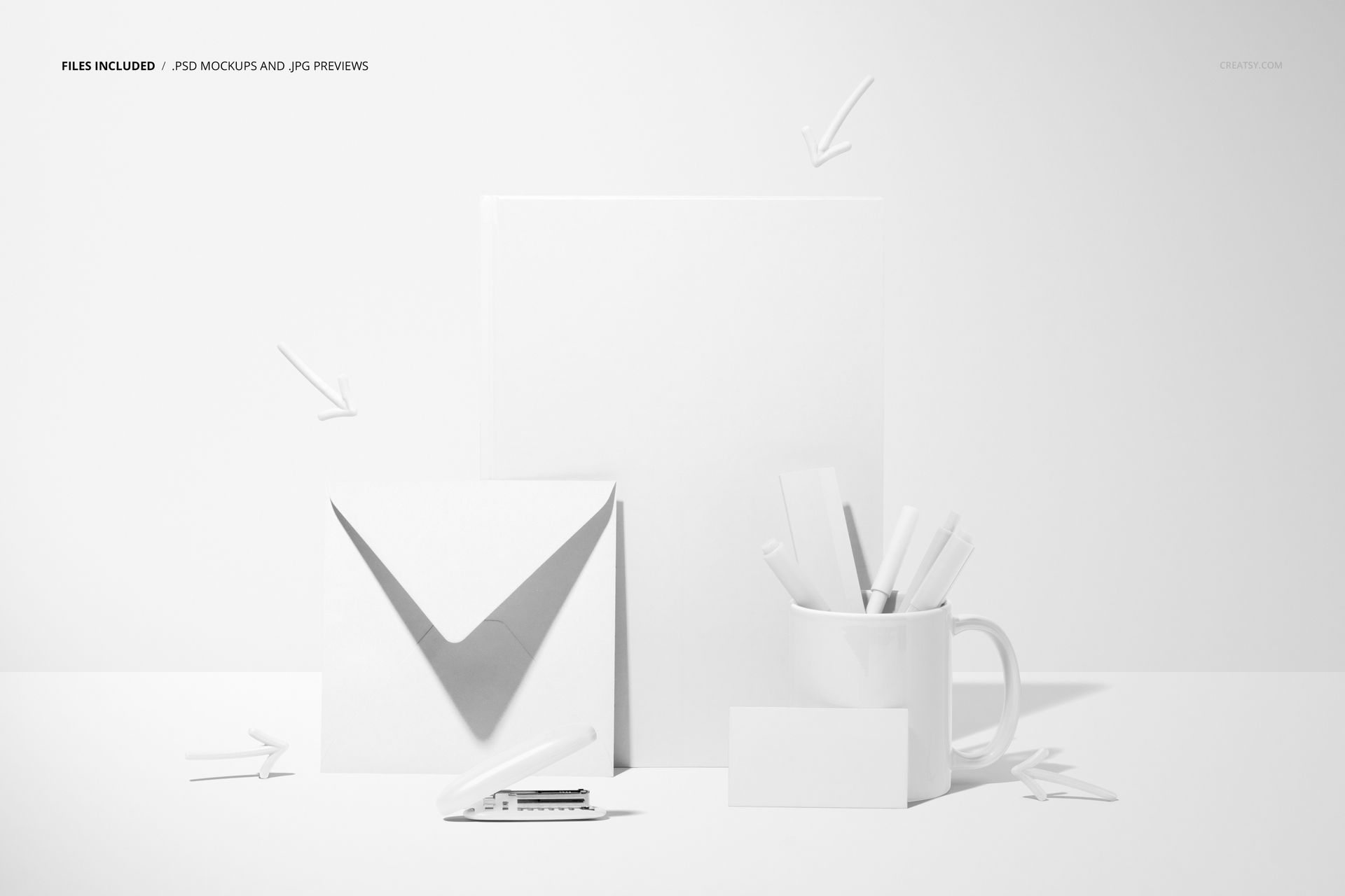 Top view of a stationery mockup with a notebook, envelope, mug holding pens, and a blank business card on a white desk.