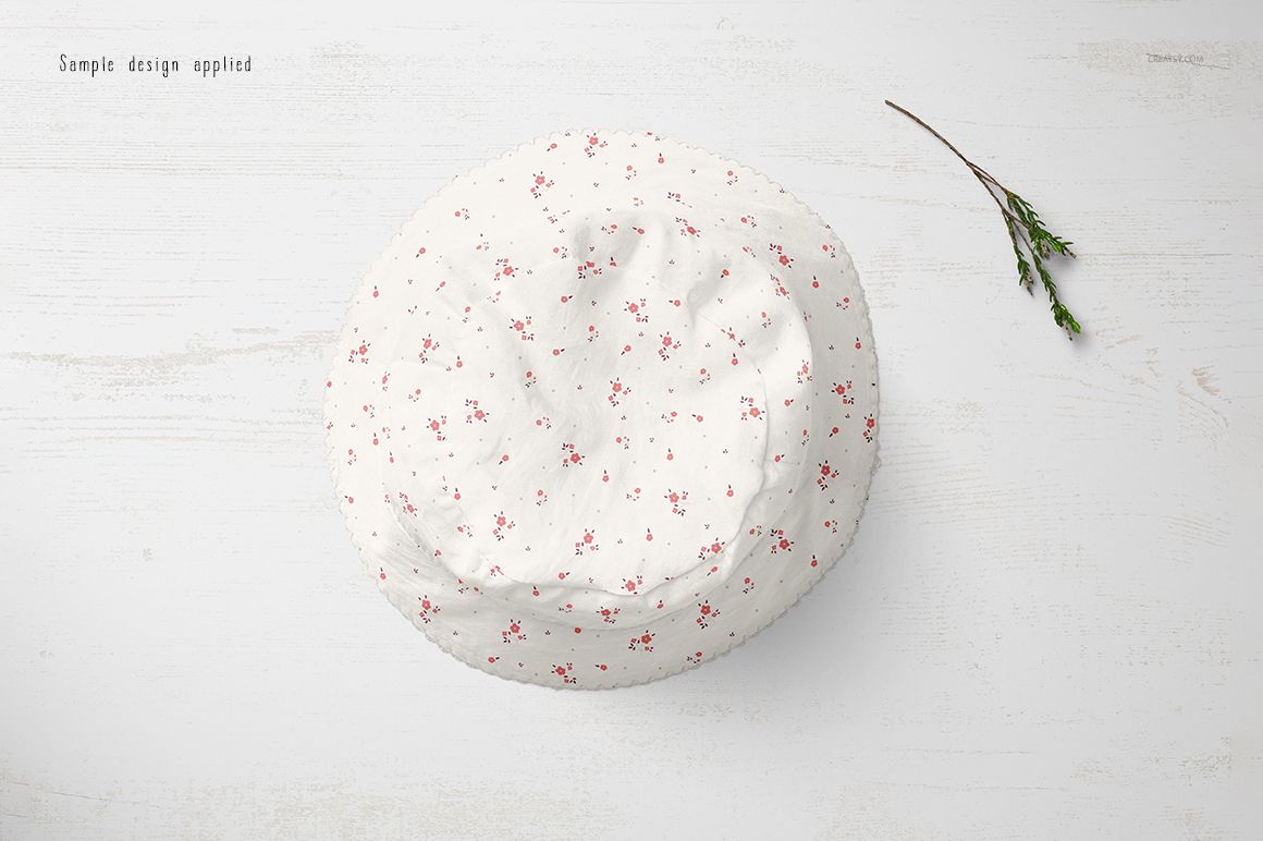 Baby hat mockup featuring a round shape, white fabric, and scattered tiny red flowers, shown from above on a pale background.