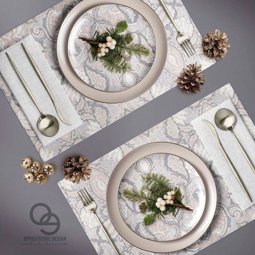 Placemat napkin plate mockup showing two place settings with light patterned placemats, beige plates, and festive pine accents.