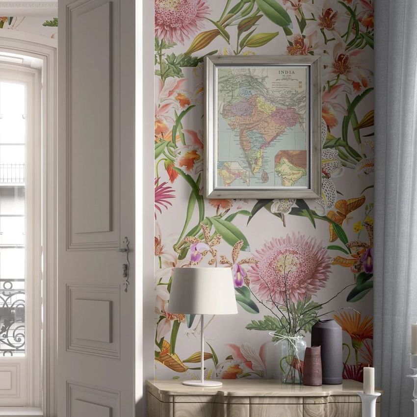 Classical apartment wallpaper mockup showing a floral patterned wall with a framed map, table lamp, and vase on a cabinet.
