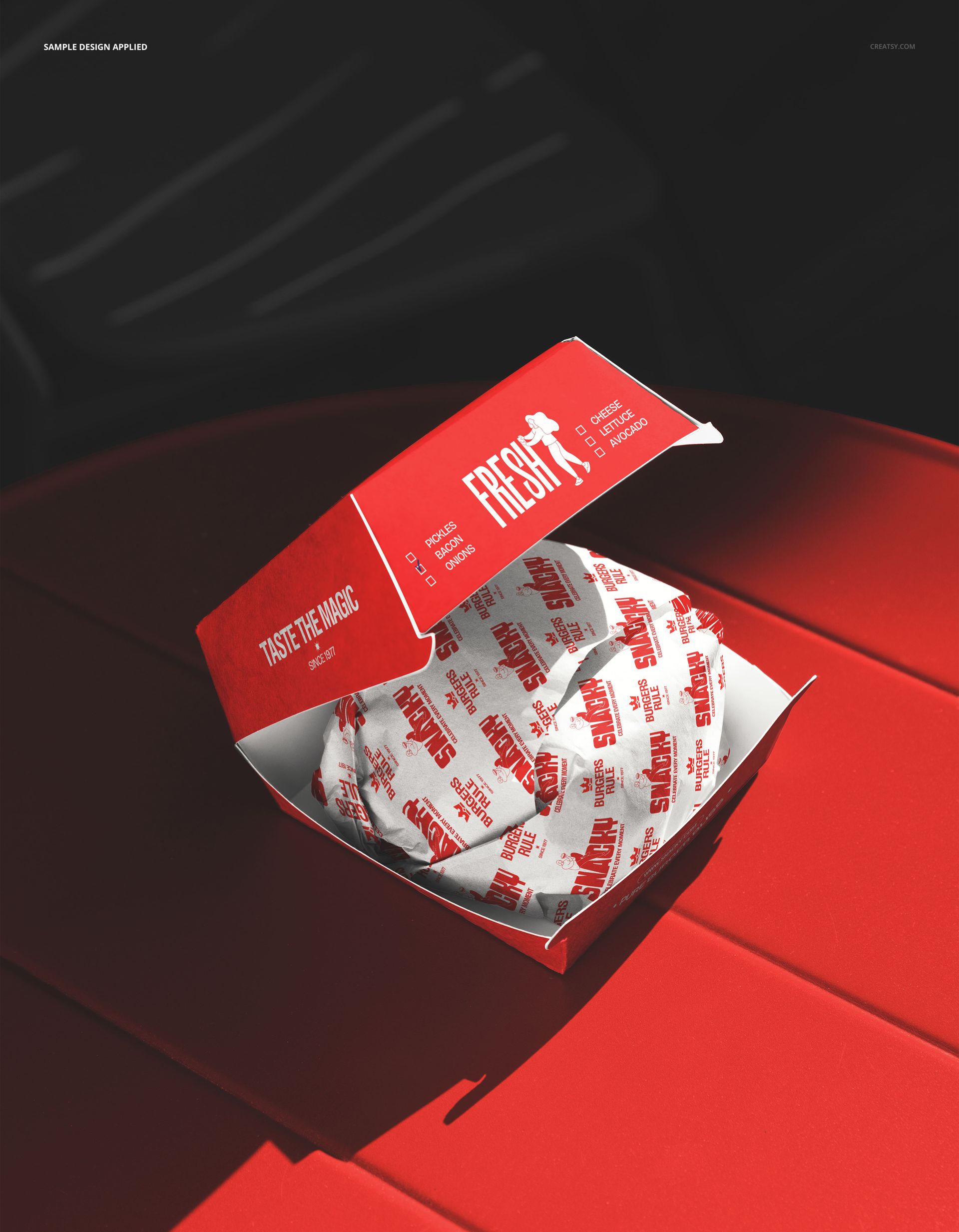 Red and white burger box mockup with a wrapped burger, viewed from above on a vibrant red tabletop surface.