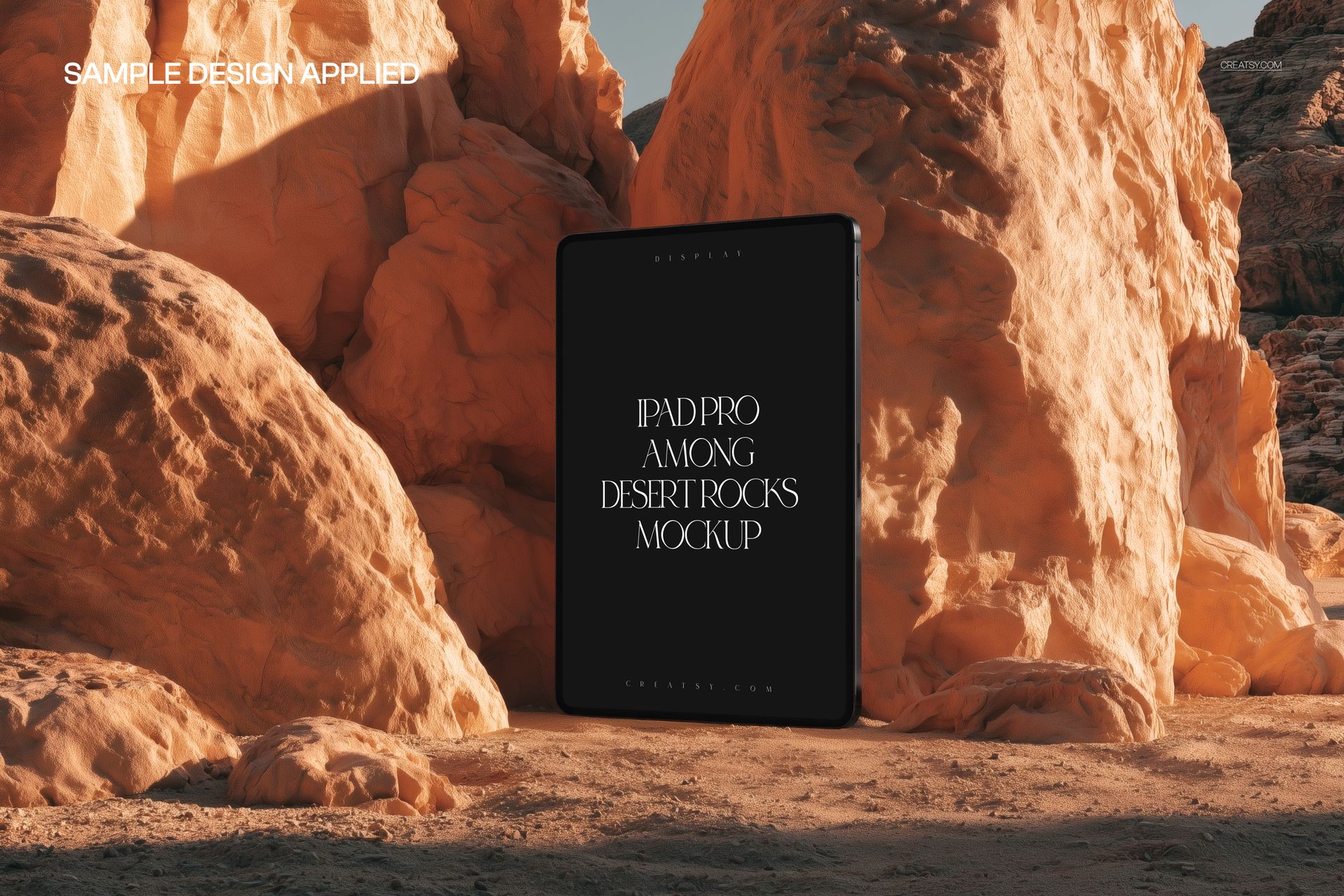 PSD mockup of an iPad Pro placed vertically between textured desert rocks, illuminated by natural sunlight.