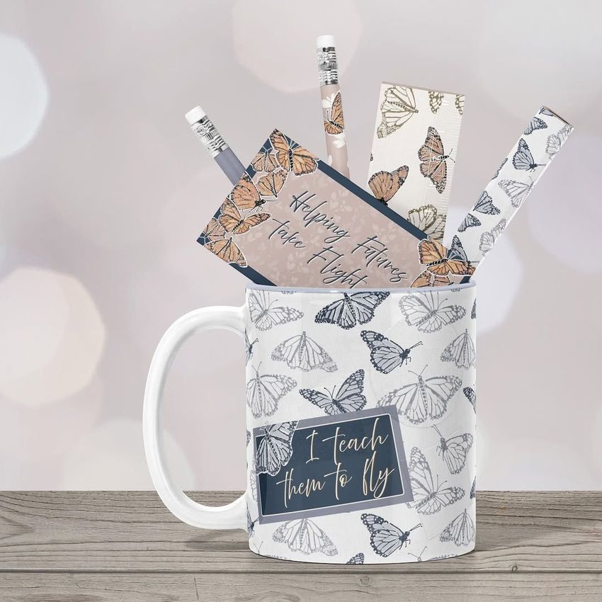 Mug mockup featuring a white mug with butterfly illustrations, filled with stationery items decorated in matching butterfly patterns.