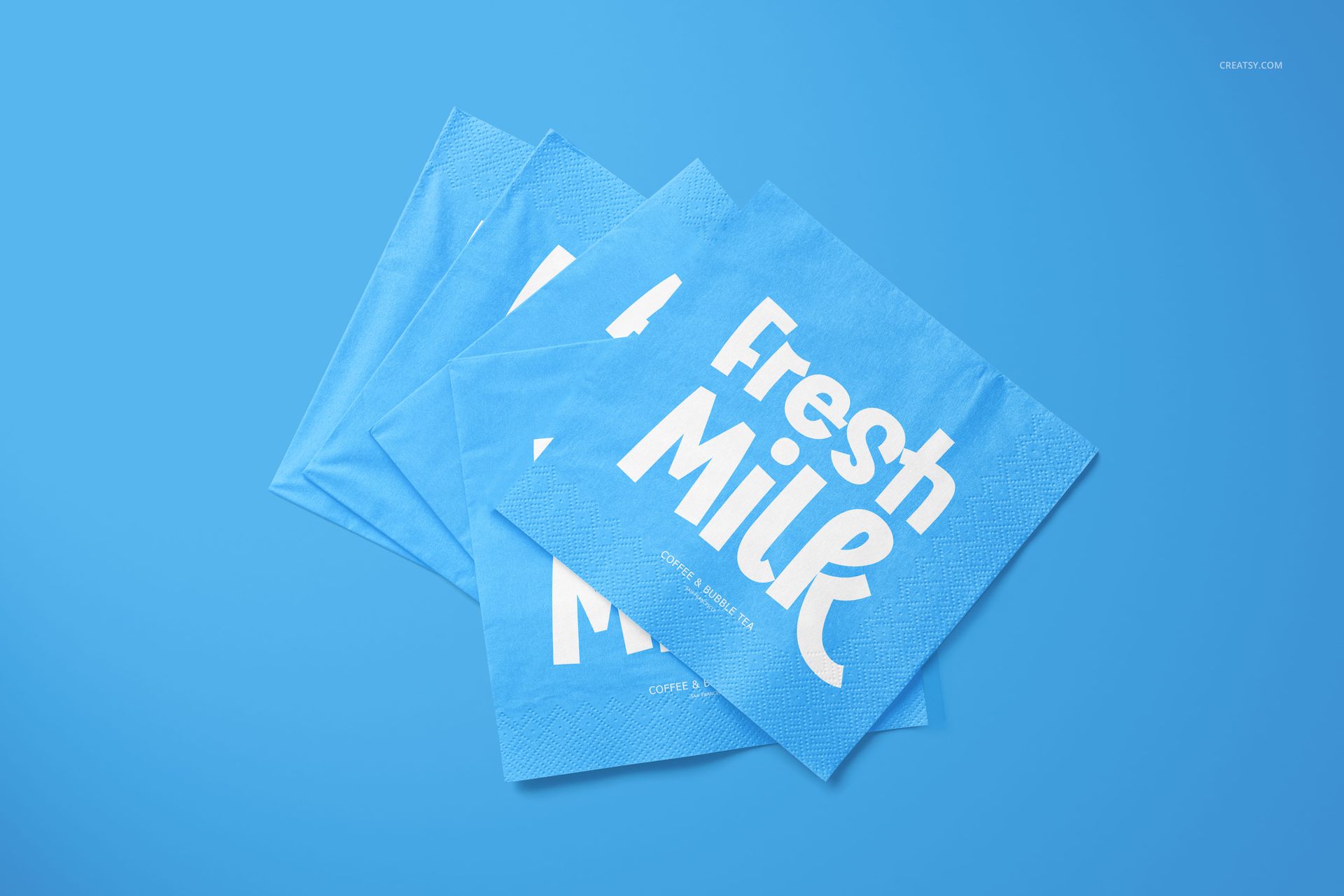 Napkin PSD mockup with stacked blue napkins, white graphic text, and embossed edge detailing on a blue backdrop.