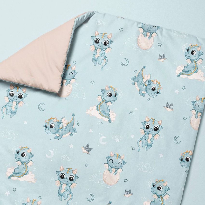 Baby duvet cover mockup featuring a pastel blue fabric with playful baby dragon illustrations, stars, and moons on a flat surface.