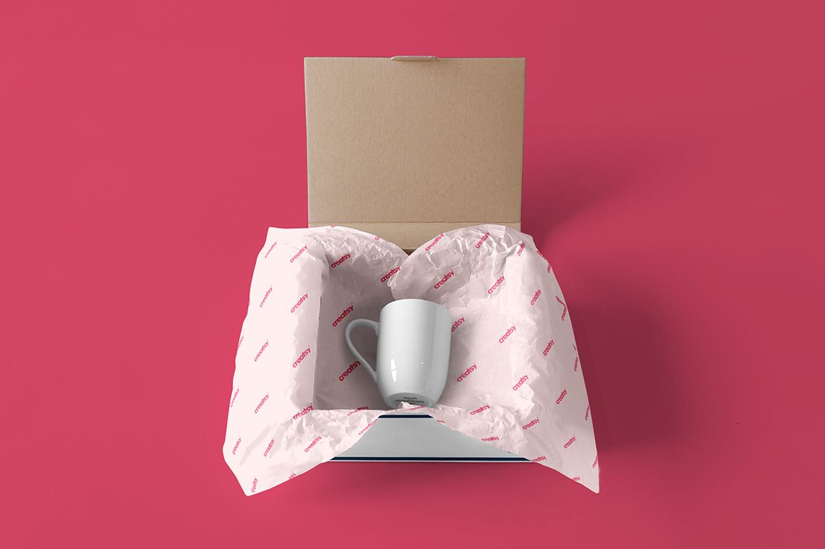 Mailing box mockup showing a white ceramic mug nestled in branded wrapping paper, set on a vibrant pink backdrop.
