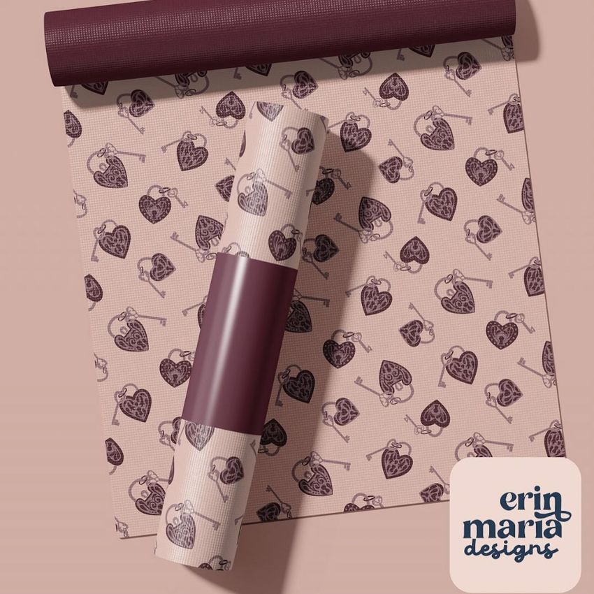 Yoga mat mockup featuring a rolled and unrolled mat with a repeating heart and key pattern in burgundy tones on a pink background.