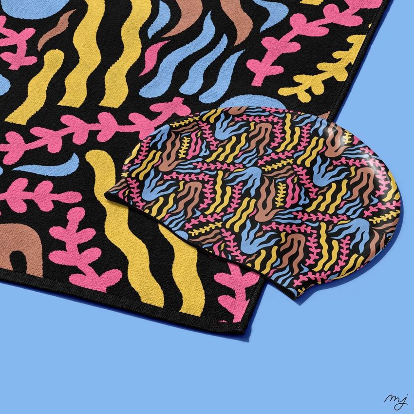 Swim cap mockup with a colorful abstract pattern in blue, pink, and yellow, placed on a matching patterned towel.