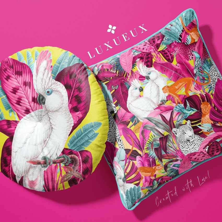 Square and round velvet cushion mockup featuring colorful tropical bird and animal illustrations on a vibrant pink background.