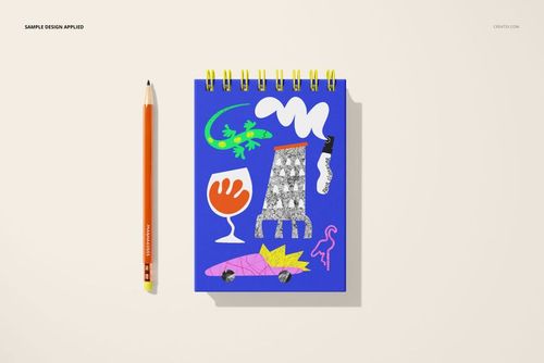 Spiral ring notebook mockup with vibrant blue cover and assorted graphic designs, displayed next to a pencil on a light surface.