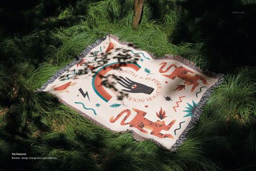 Jacquard blanket mockup featuring a playful design with tigers and abstract shapes, placed on lush grassy ground.