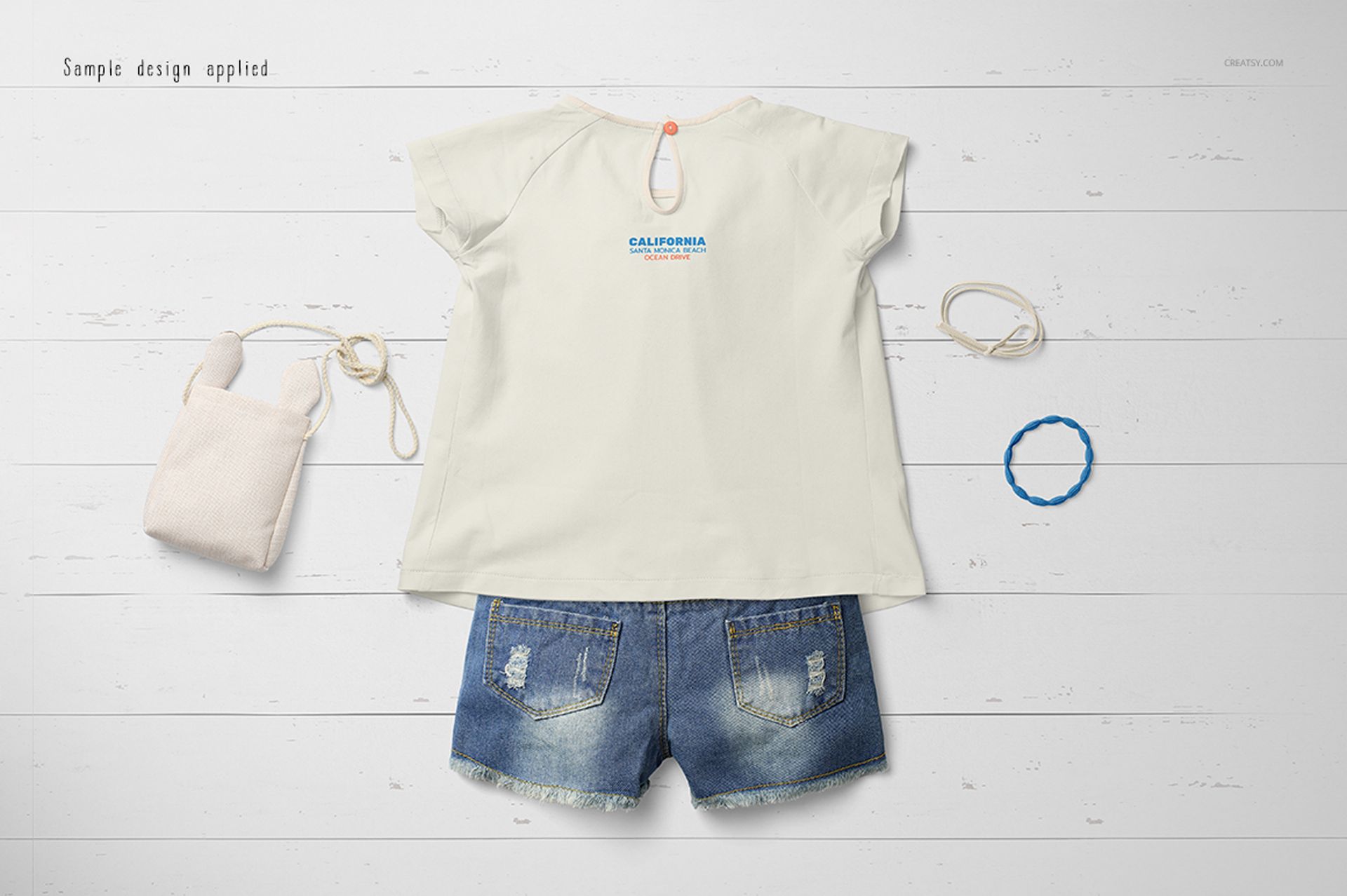 Baby summer set mockup featuring a cream short-sleeve shirt and blue denim shorts, displayed on a white wooden surface.