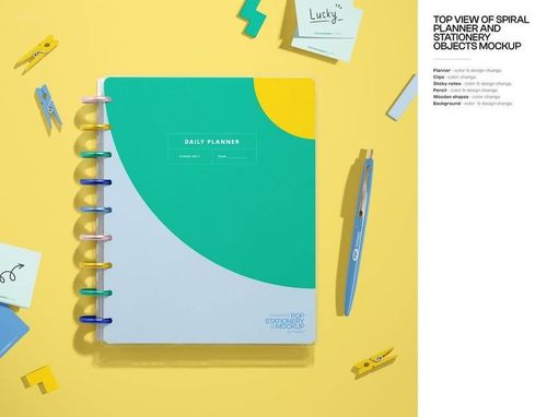 PSD mockup showing a spiral notebook and assorted stationery like pens, clips, and erasers arranged neatly from above.