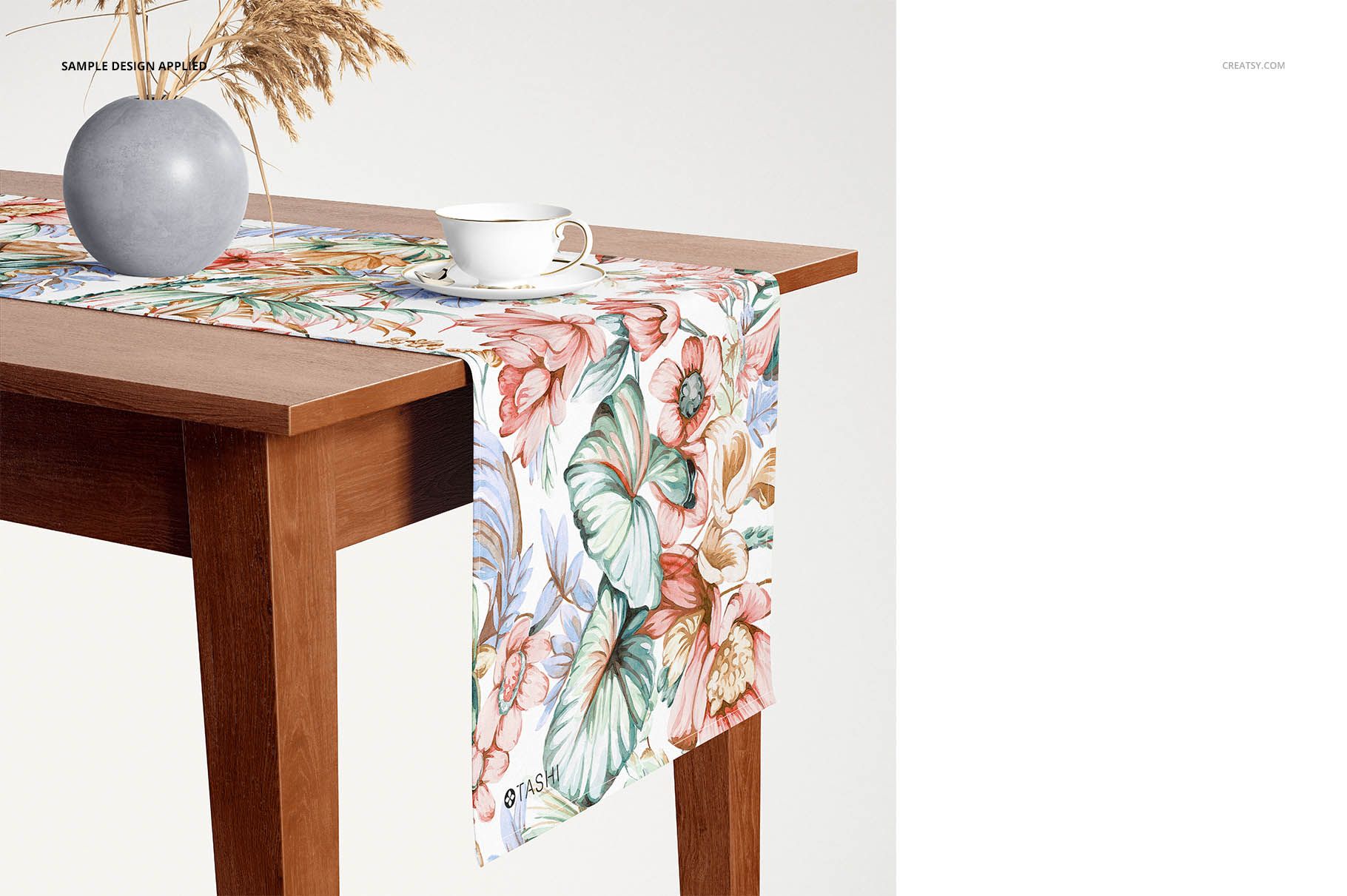 Floral table runner mockup on a rectangular wooden table, featuring pastel flowers and green leaves, front perspective.
