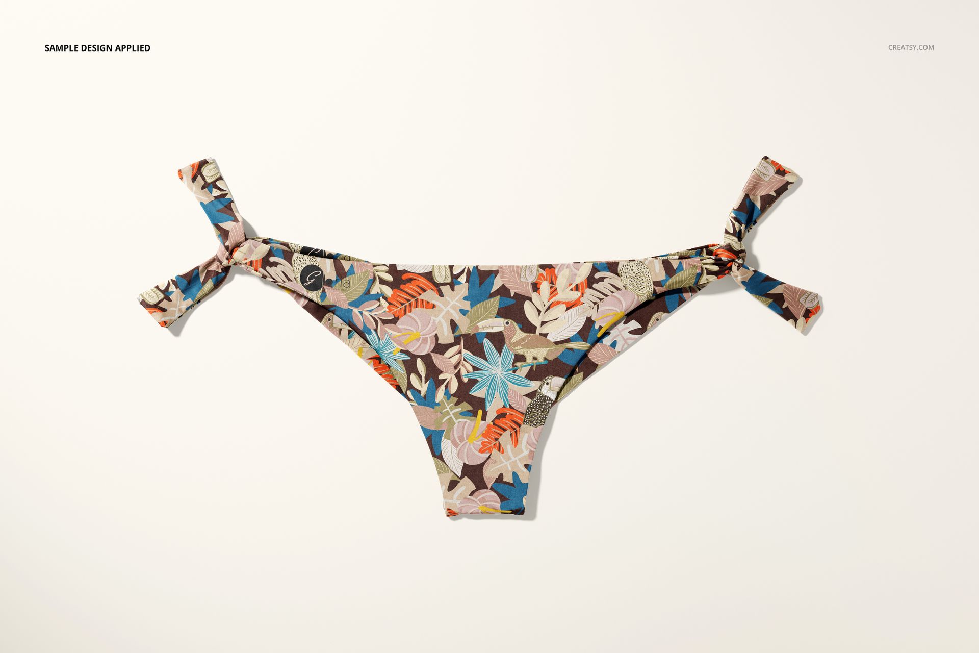 Front view of a bikini bottom mockup with side tie details, featuring a colorful floral pattern on a light background.