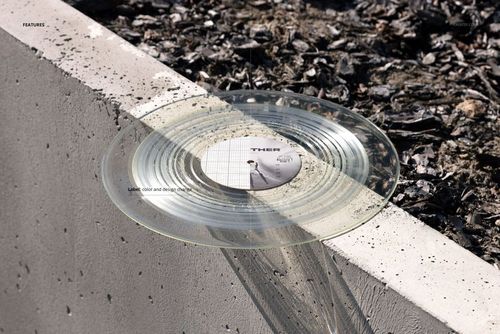 Transparent vinyl record mockup placed on a concrete ledge, surrounded by urban gravel and sunlight reflections.