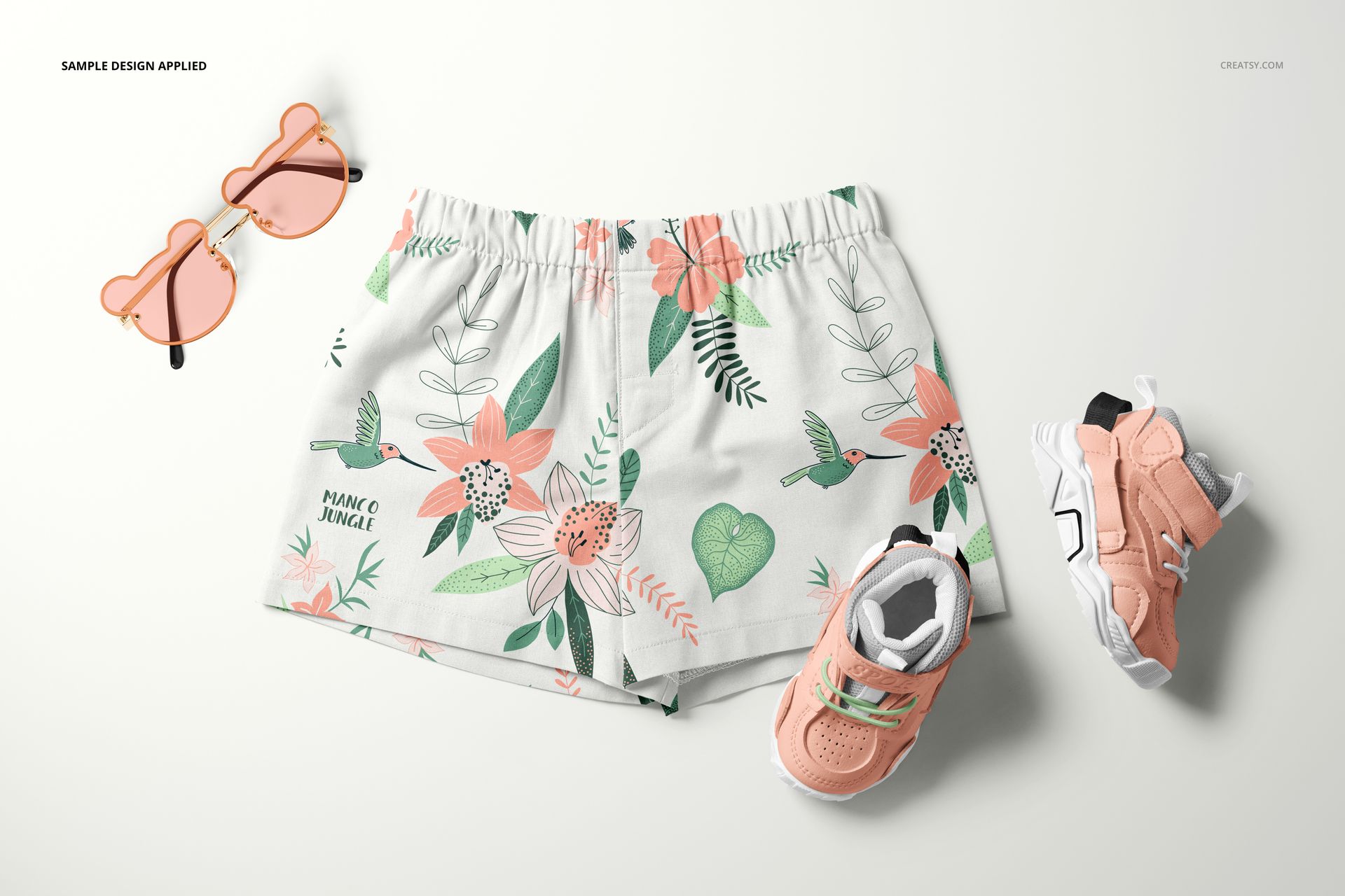 Baby and kids shorts mockup featuring a botanical print, shown from above with matching peach shoes and sunglasses.