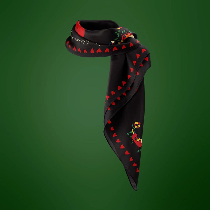 Silk scarf mockup featuring a black scarf with red heart patterns and small colorful illustrations, displayed on a green background.