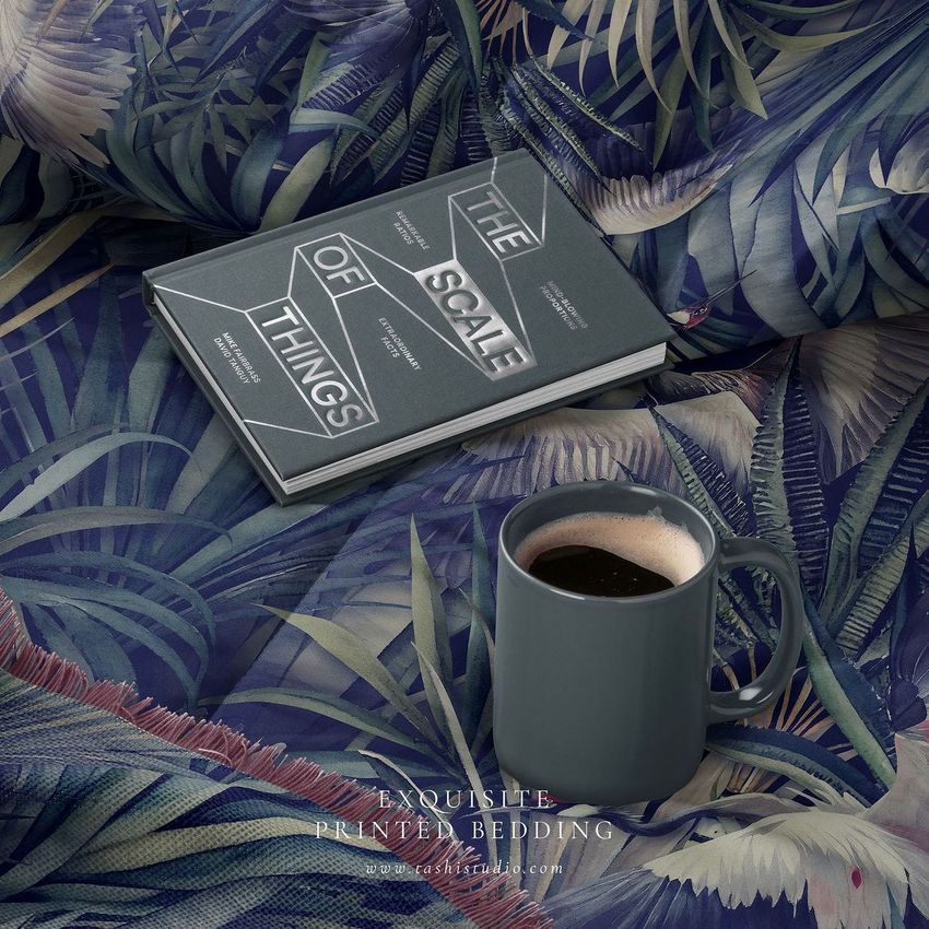 Microfiber comforter mockup featuring a dark mug of coffee and a closed book on a bed with tropical leaf patterns.
