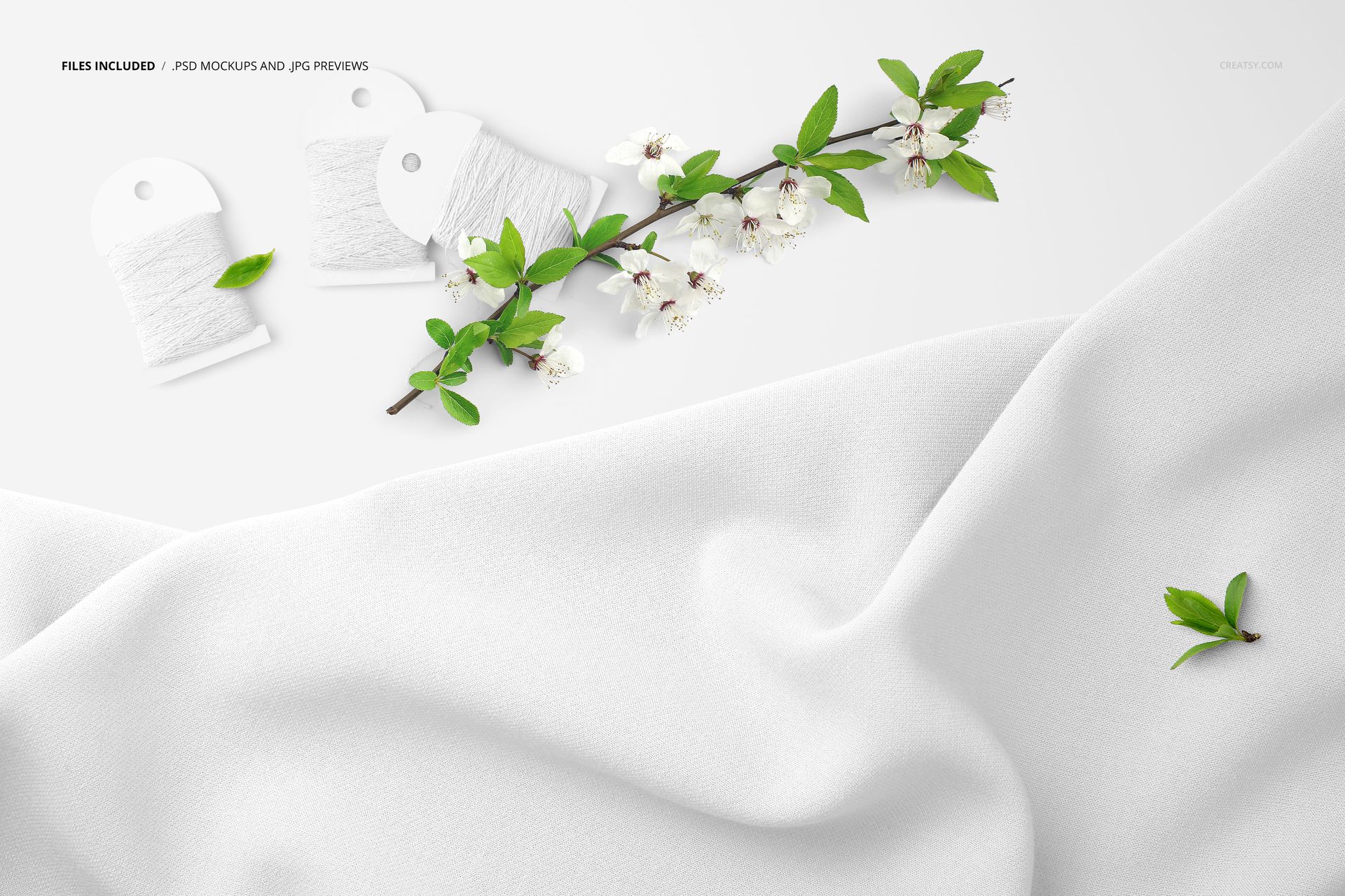 Draped white fabric mockup with two thread cards and blooming branches, shown from a top view on a light background.