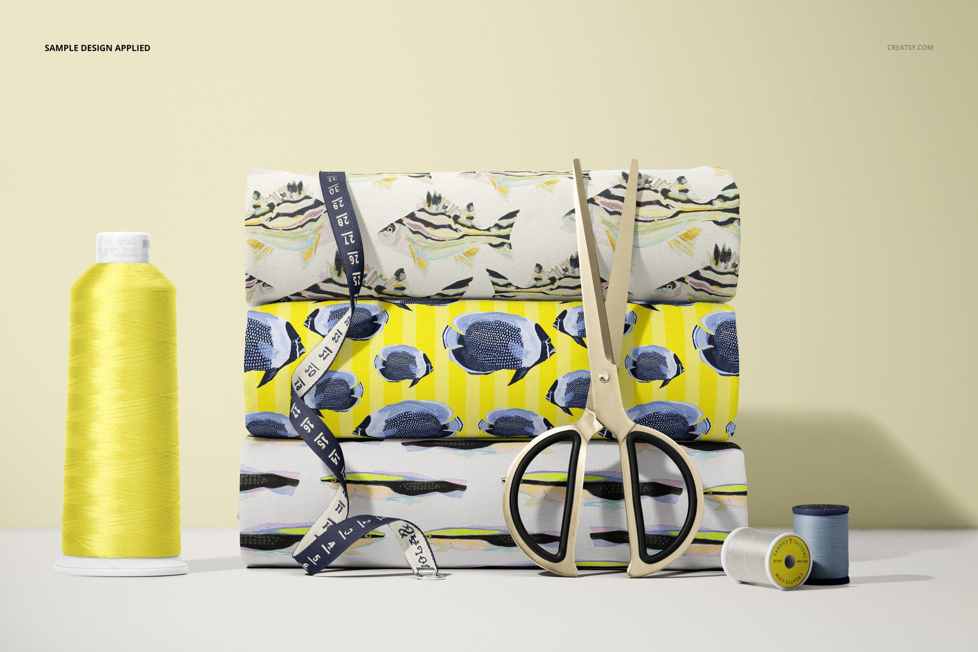Front view of three folded patterned jersey fabrics, scissors, measuring tape, and spools of thread in a mockup scene.