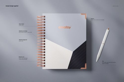 Wire-bound planner mockup with a geometric cover design in white, black, and copper tones, shown from above on a gray surface.