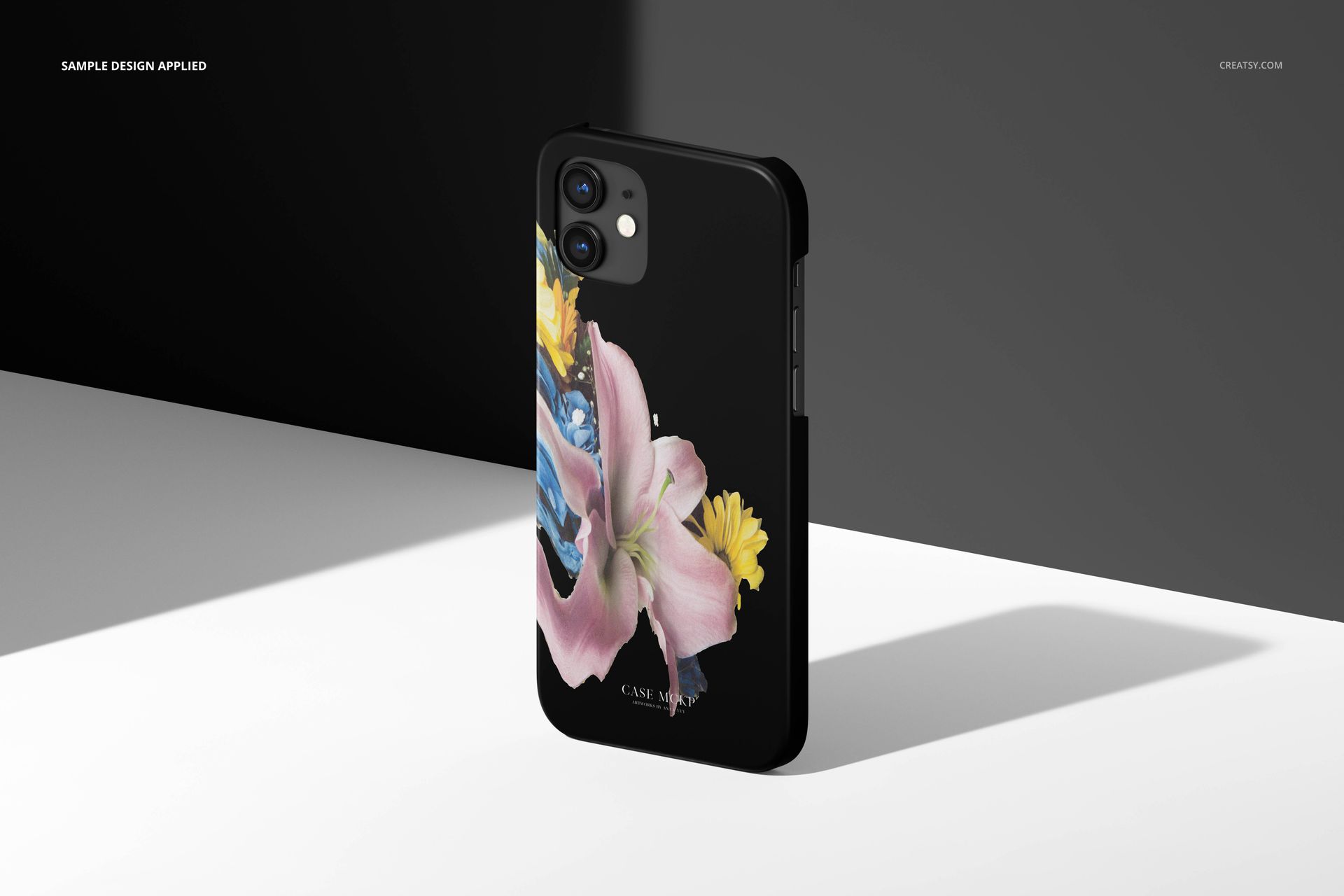 iPhone 12 matte snap case mockup featuring a black case with a floral design, shown in angled light on a white surface.