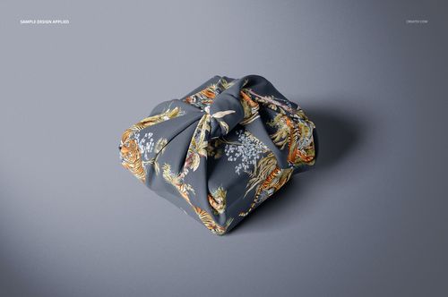Fabric gift wrap mockup featuring a square package wrapped in dark fabric with floral and tiger patterns, top view.