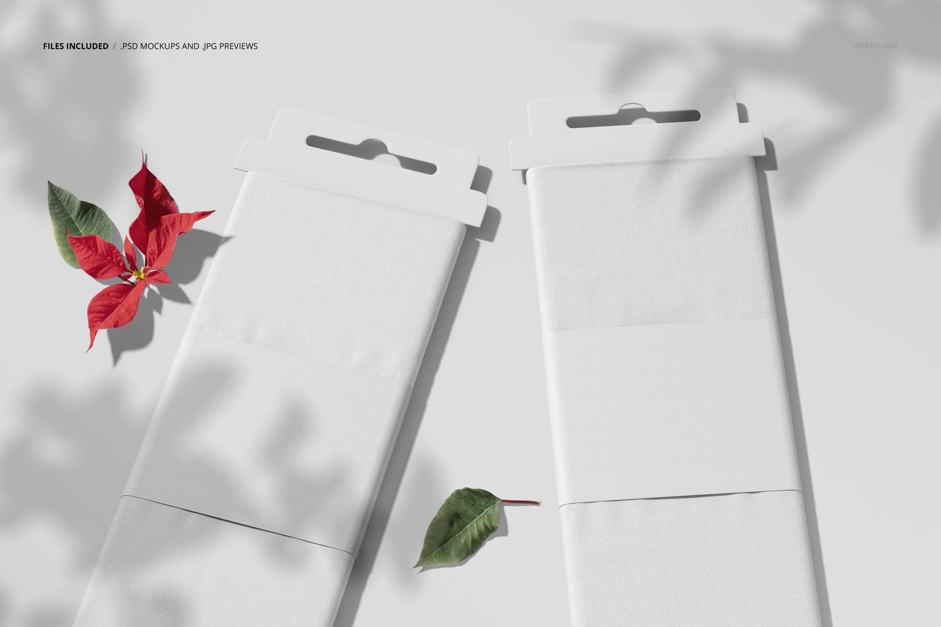 Fabric bolts mockup showing two white textile rolls with packaging, shadows, and scattered leaves for a realistic presentation.