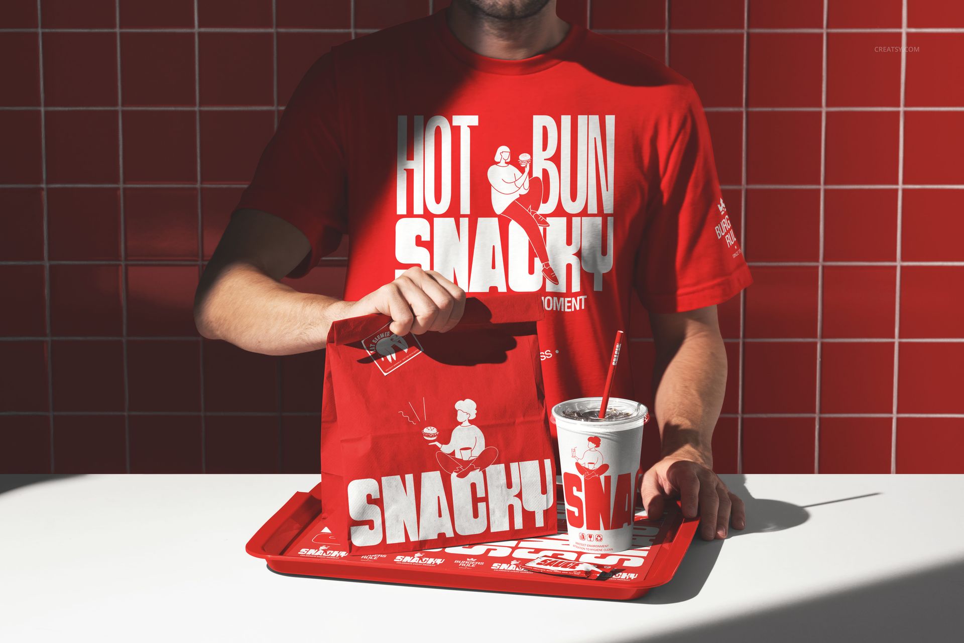 Red fast food restaurant branding mockup featuring a takeout bag, cup with straw, and tray on a white counter.