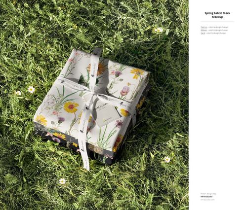 PSD mockup featuring multiple fabric samples with botanical prints, arranged in a neat stack on a lawn.