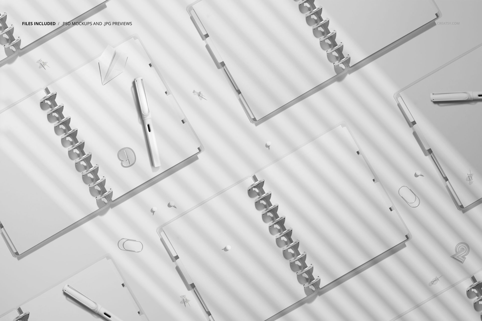 Flat lay of multiple spiral planners mockup with open pages, scattered pens and clips, shown in soft gray shades.