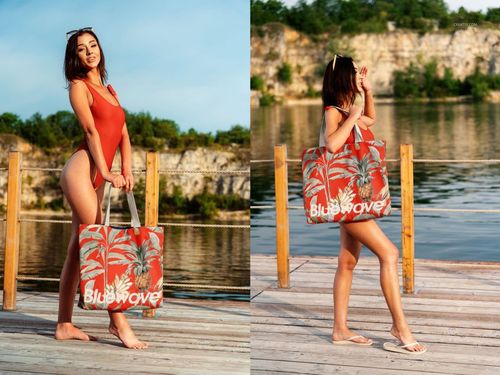 PSD mockup of a large cotton tote bag featuring a bold red palm print and white lettering, displayed lakeside.