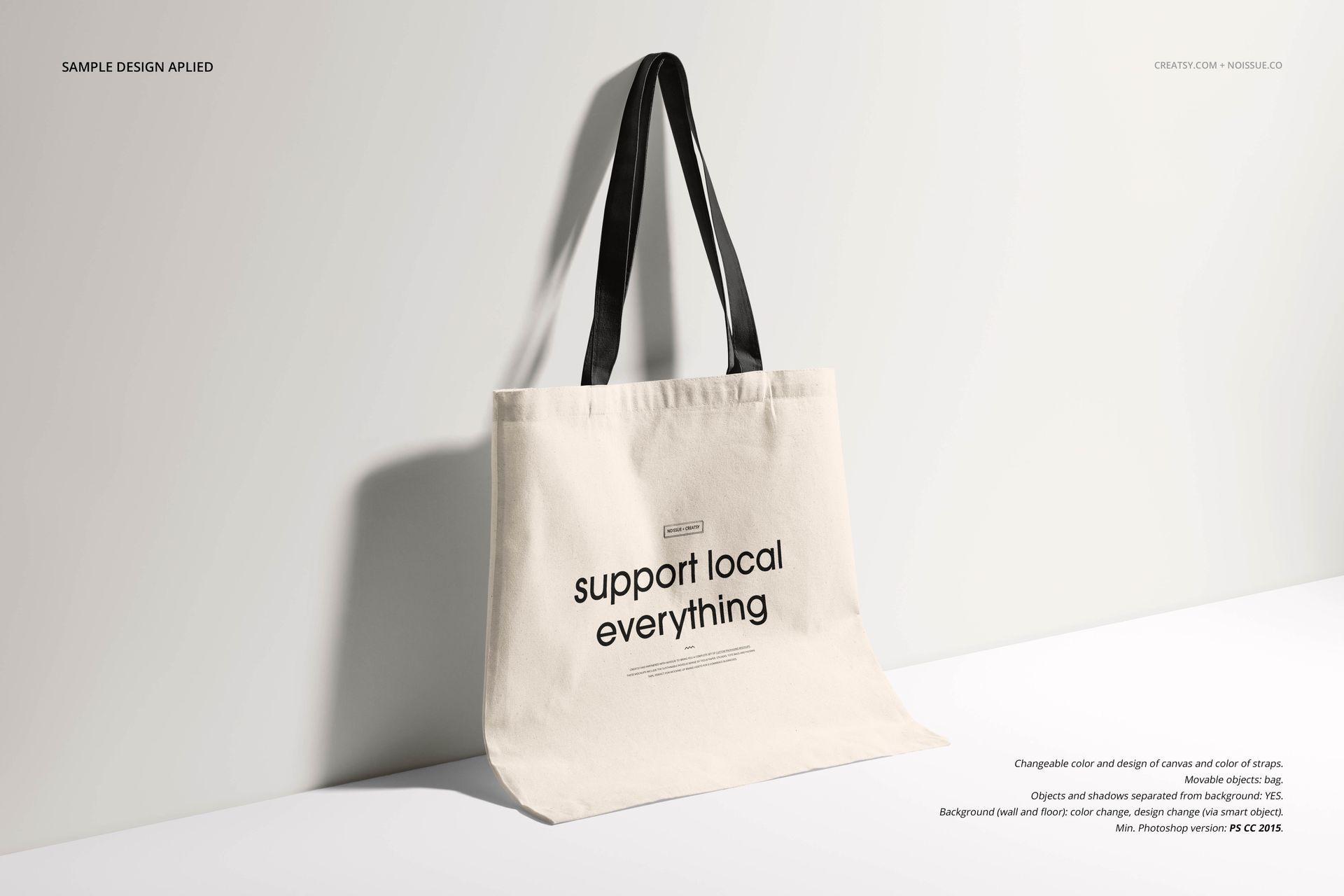 Neutral-colored tote bag mockup with black straps, shown from the front with shadow detail and simple text print.