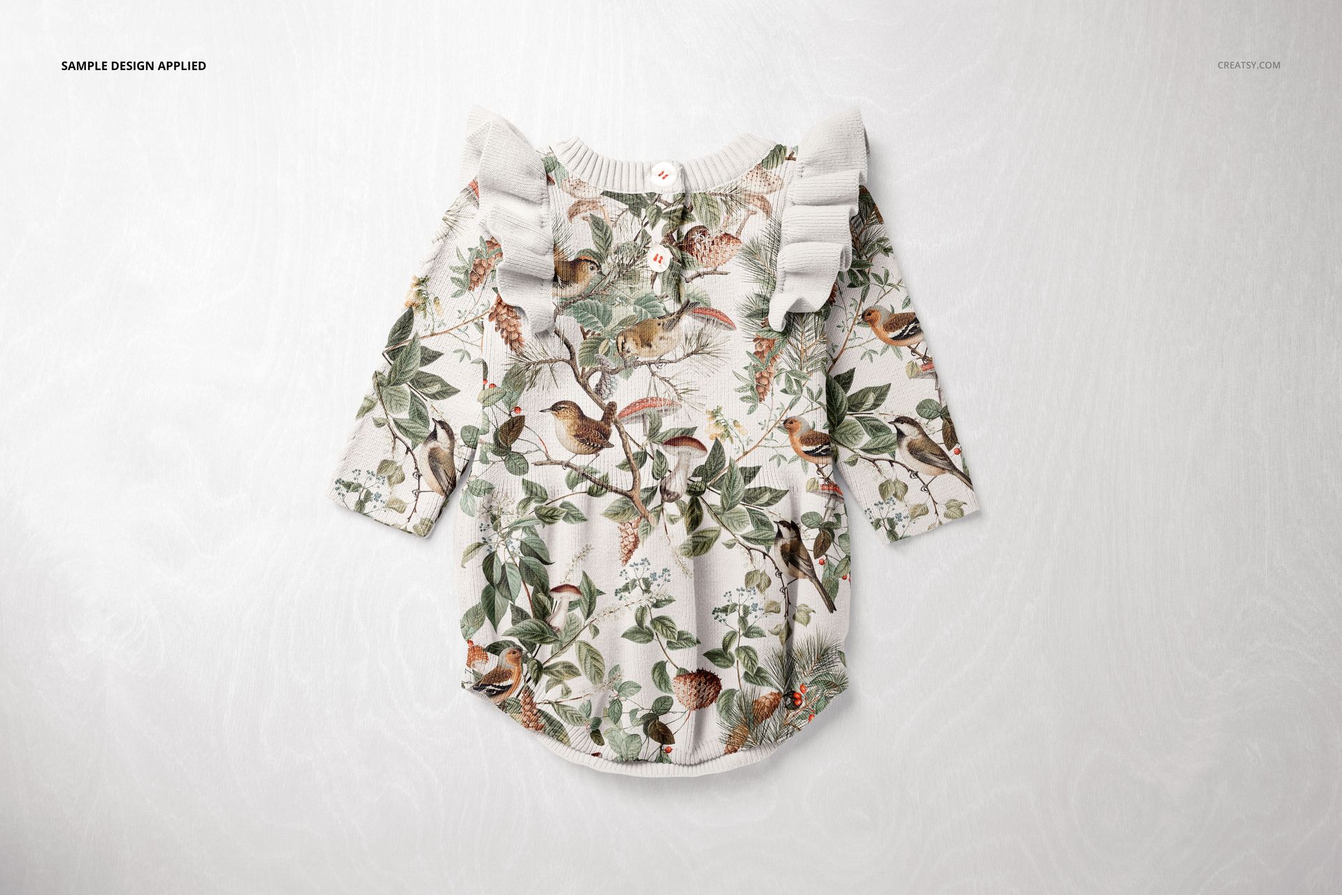 Knitted romper mockup displayed flat, showing a detailed botanical and bird print with ruffled shoulders on a light surface.