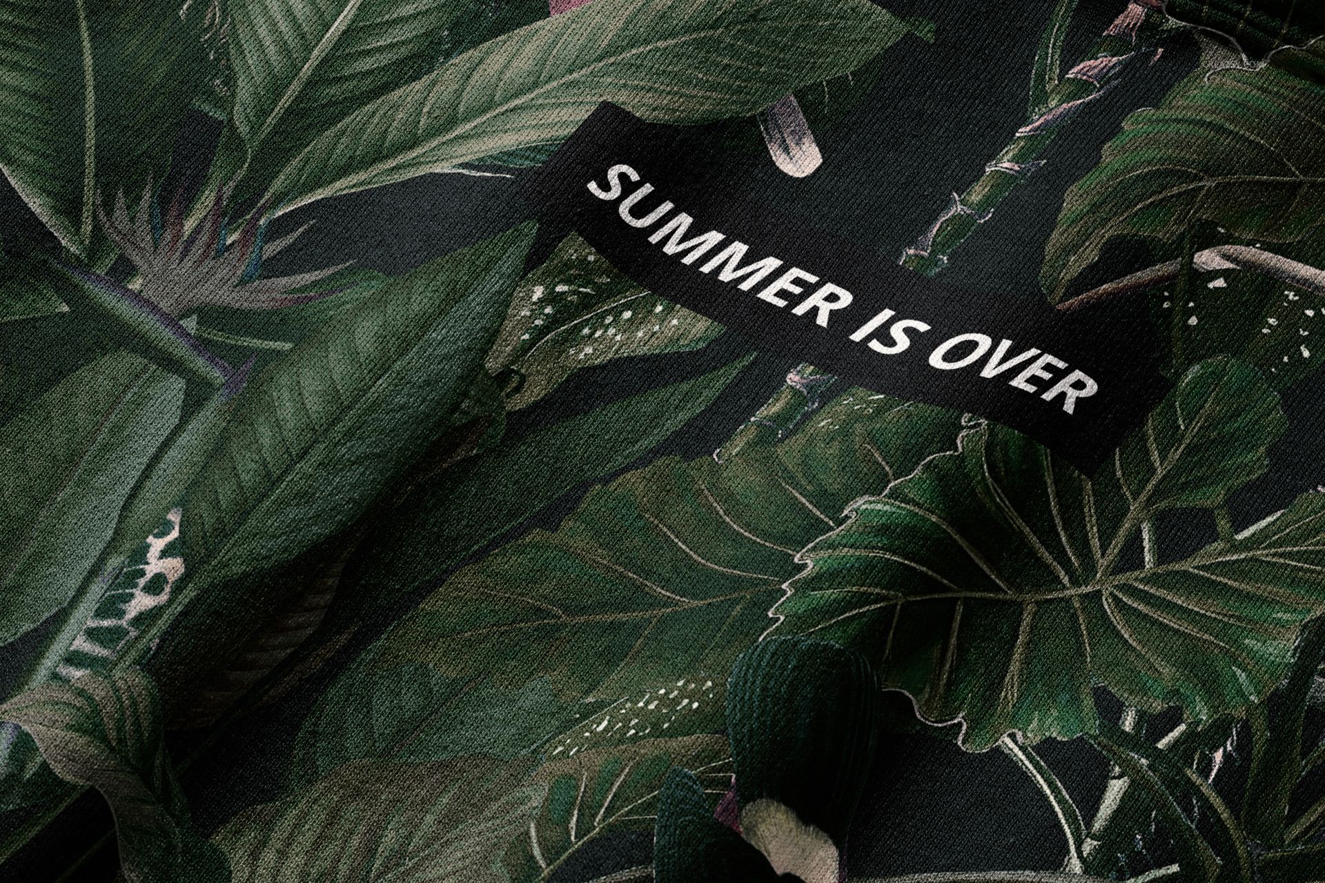PSD mockup of a hoodie showing realistic leaf patterns and a sewn-on black tag with bold lettering.
